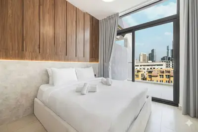 Bedroom with wood panel feature wall and large window overlooking the city