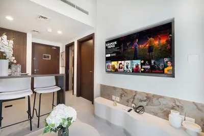 Wall-mounted TV with a streaming menu visible, mounted beside the entryway hallway