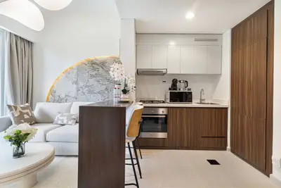 Open kitchen with walnut lower cabinets, white uppers and a two-seat bar counter