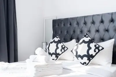 Close-up of the tufted grey headboard with folded white towels and geometric cushions