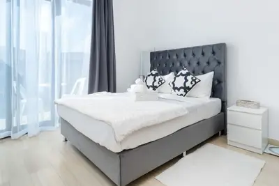 Double bed with a tufted grey headboard and black and white patterned cushions
