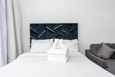 Bed with folded white towels and a dark tufted headboard