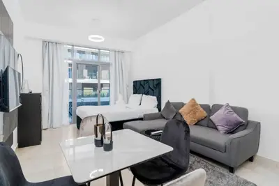 Open-plan studio with dining table, sofa, and bed by the window