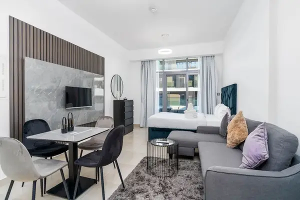 Living area with grey sofa, marble dining table, and wall-mounted TV