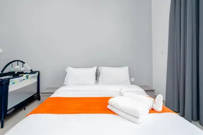 Close view of double bed with folded white towels on orange runner
