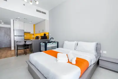 Studio sleeping area with double bed and open kitchen with yellow backsplash behind