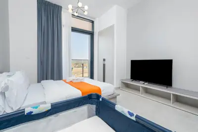 Two beds arranged side by side with a flat-screen TV and open balcony door