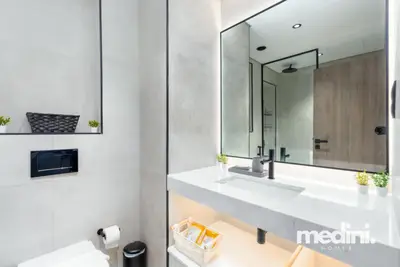 Bathroom with lit mirror, wall-hung toilet, and marble-look vanity