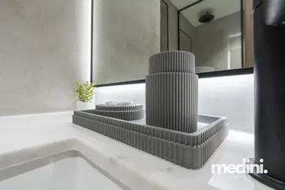 Bathroom countertop with textured grey accessories and backlit mirror