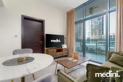Dining and living area seen from the entrance, with a flat-screen TV and city view