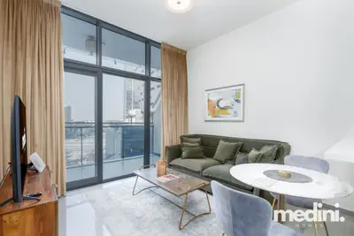 Living room with green sofa, round dining table, and floor-to-ceiling balcony doors