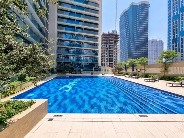 Outdoor pool flanked by high-rise towers and poolside loungers
