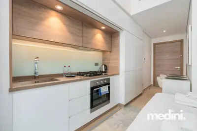Compact kitchen with white cabinets, gas hob, oven, and a glass splashback