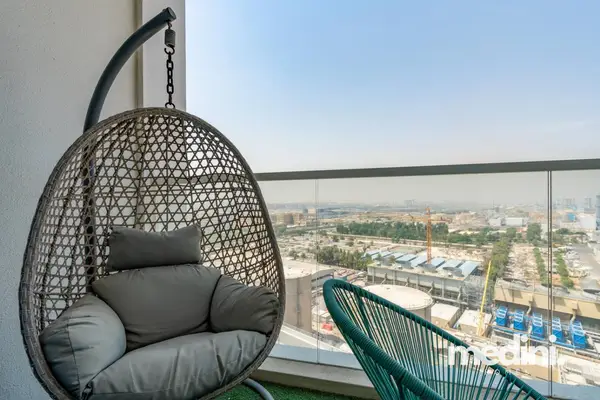 Balcony with a hanging rattan egg chair and open city view