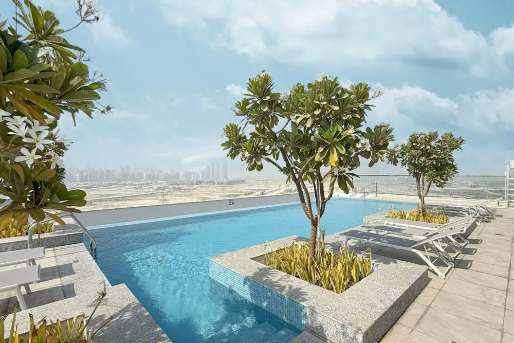 Rooftop pool with sun loungers, planted trees, and a wide desert horizon