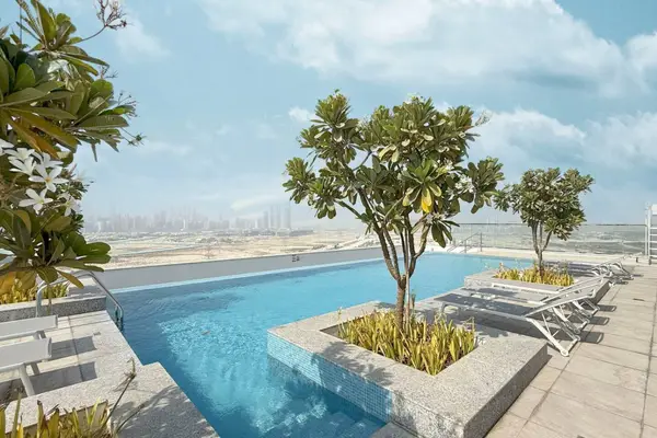 Rooftop pool with sun loungers, planted trees, and a wide desert horizon