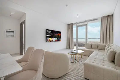 Living room with a large sectional sofa, wall-mounted TV, and a glazed balcony door