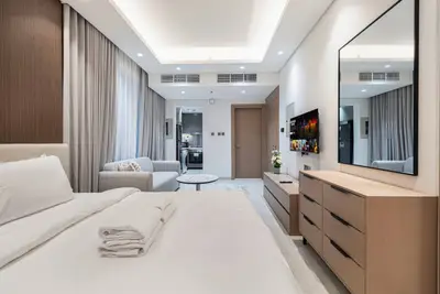 Studio seen from the bed, showing the dresser, TV and seating area toward the kitchen