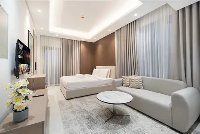 Studio living area with a double bed, grey sofa, marble coffee table and wall-mounted TV