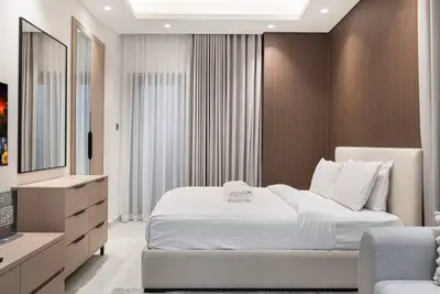 Bedroom corner with upholstered headboard, white linens and wood-panel accent wall