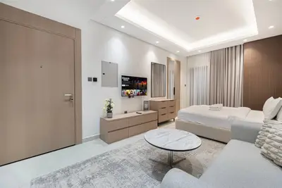 Wide studio view from the seating area with the entrance door and bed visible