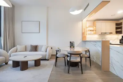 Open-plan living room with curved sofa, round dining table, and kitchen beyond