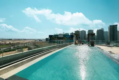 Rooftop infinity pool with glass railing and city skyline in the background