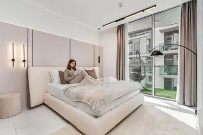 Bedroom with upholstered bed, blush wall panels, and sliding balcony door