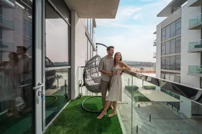 Balcony with a hanging egg chair and glass railing overlooking neighbouring buildings