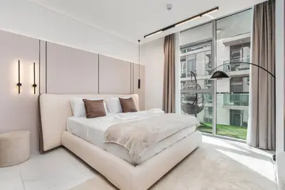Bedroom seen from the foot of the bed, with arc floor lamp and glass balcony door