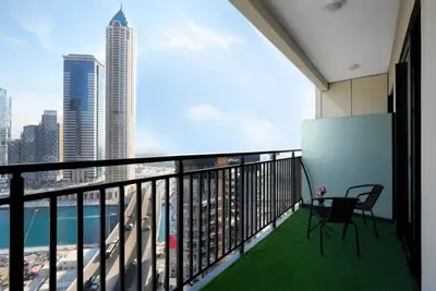 Open balcony with two rattan chairs, artificial grass, and canal and tower views