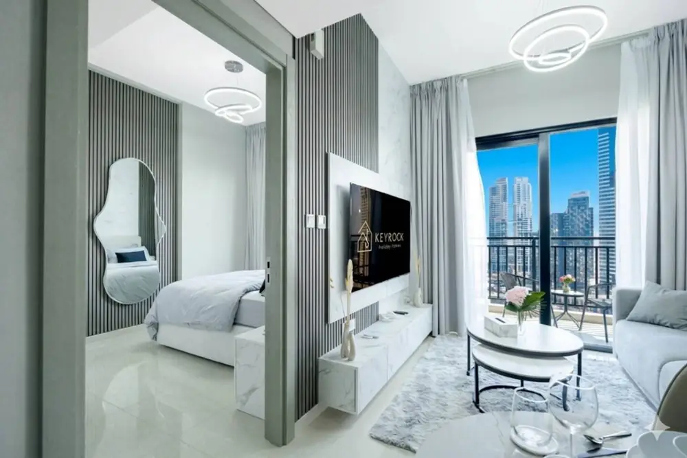 Living room with grey sofa, round coffee table, wall-mounted TV, and balcony view