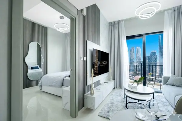 Living room with grey sofa, round coffee table, wall-mounted TV, and balcony view