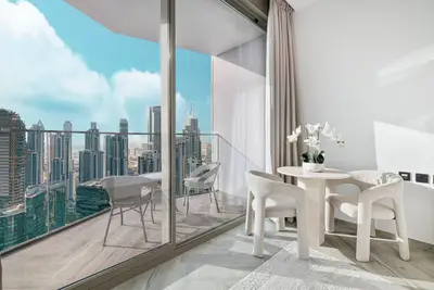Living area with round dining table, sculptural chairs, and an open balcony view