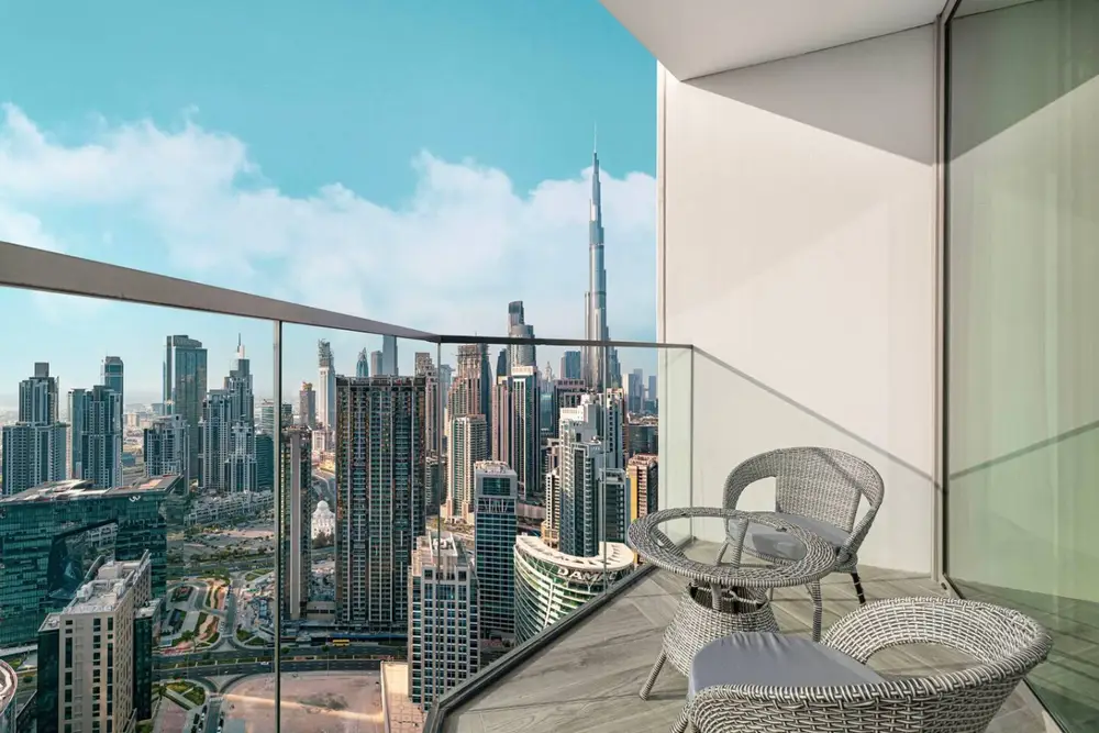 Glass-railed balcony with two chairs and a wide city skyline panorama