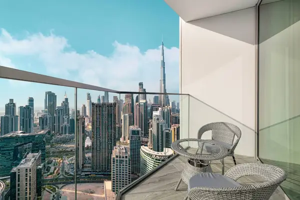 Glass-railed balcony with two chairs and a wide city skyline panorama