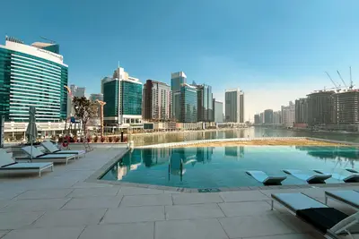 Pool terrace at ground level with sunbeds lined up beside still water