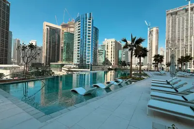 Outdoor pool deck with lounge chairs and palm trees set against high-rises