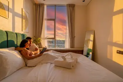Bedroom at sunset with warm light through the window and two people on the bed