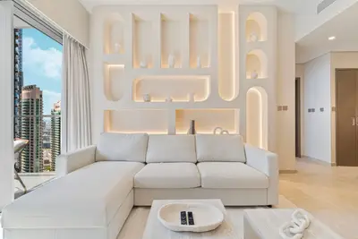 Living room featuring a lit sculptural niche wall and plush L-shaped sofa