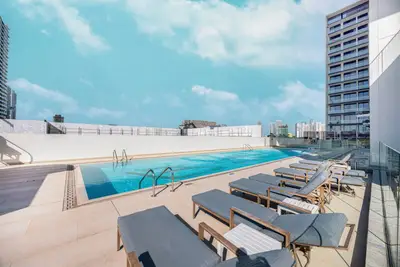 Rooftop pool deck with sun loungers and building skyline beyond