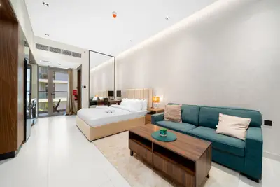 Studio room with king bed, teal sofa, wooden coffee table and recessed lighting