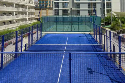 Outdoor padel tennis court with blue turf enclosed by wire fencing