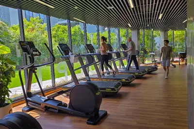 Gym with treadmills and ellipticals along floor-to-ceiling windows overlooking greenery