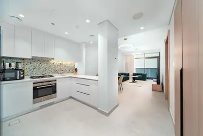 Open-plan kitchen with white cabinets, terrazzo splashback, gas hob and oven