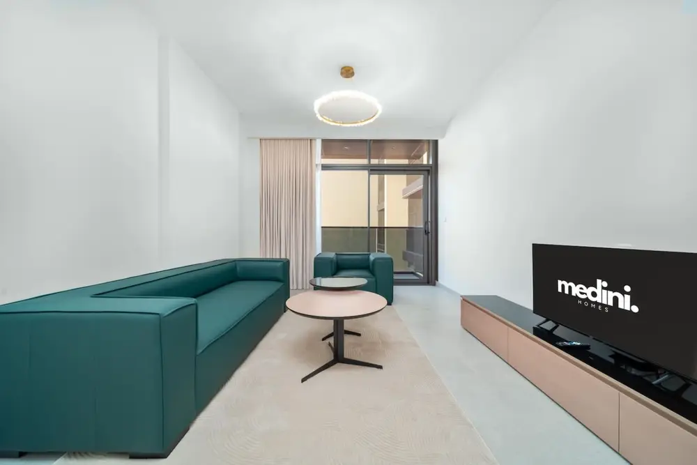 Living room with teal L-shaped sofa, round coffee table and wall-mounted TV on wood unit