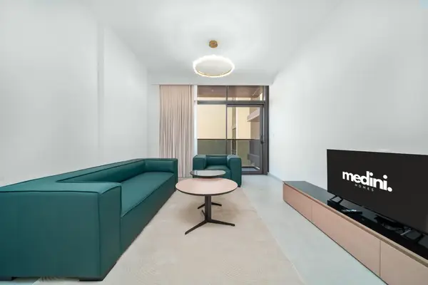 Living room with teal L-shaped sofa, round coffee table and wall-mounted TV on wood unit