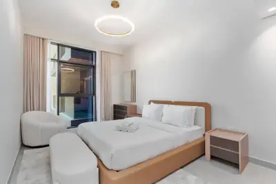 Bedroom with king bed, wooden headboard, round pendant light and balcony door