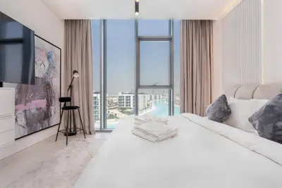 Bedroom seen from the bed, large window framing the lagoon and city skyline