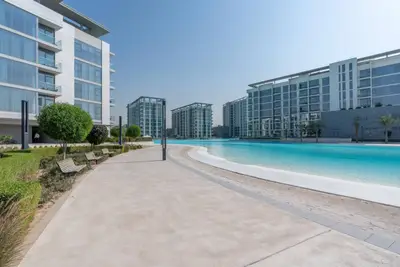 Outdoor crystal lagoon flanked by residential towers on a clear day